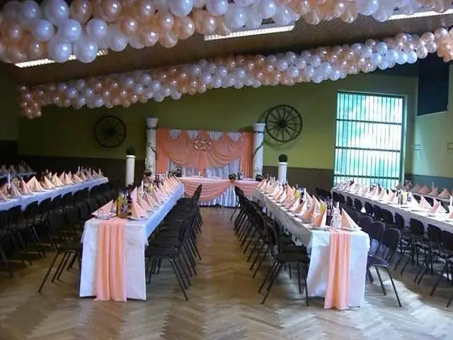 Poolhalle innen geschmcükt mit langen Tischreihen und Luftballons für eine Hochzeitsfeier